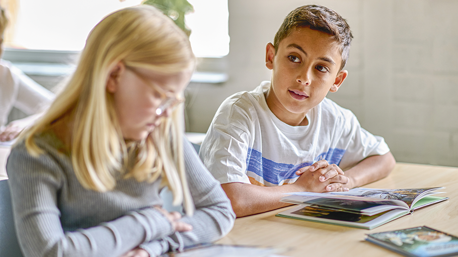 Skolbarn som läser böcker. Bilden länkar till en intervju om lässatsning inom skolan.
