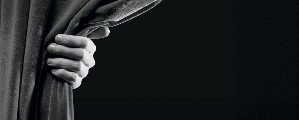 Svartvit bild på ett draperi som hålls upp av en hand