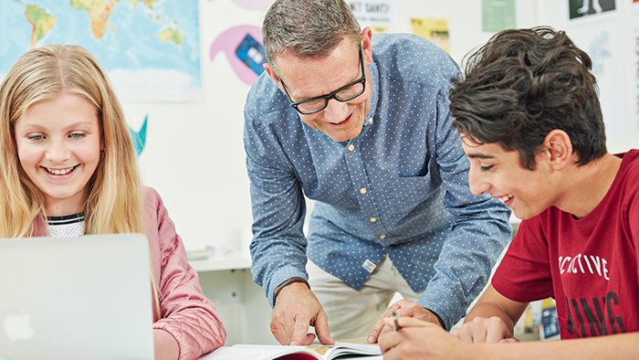 Lärare som hjälper elever som arbetar med digitala läromedel